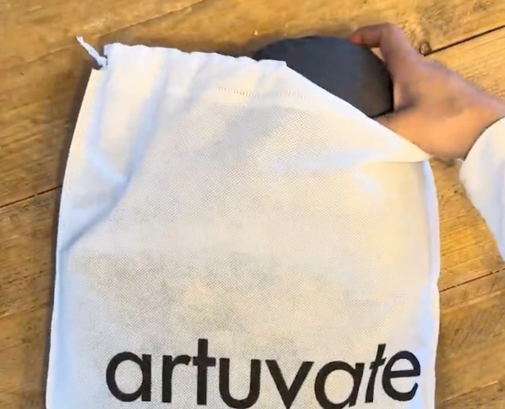 A customer photograph of the FisioRest being slid out of its white artuvate drawstring bag on a wooden floor.