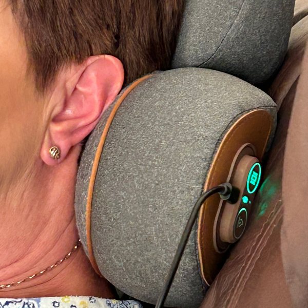 Close-up of a customer's neck resting on the device, its controls lit green.