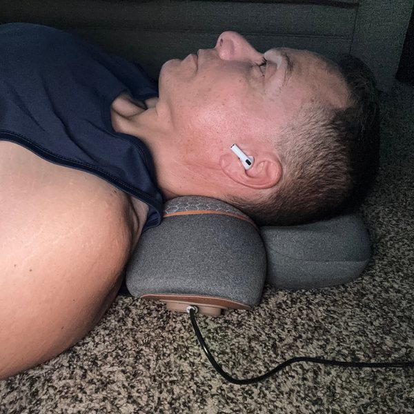 Juan, a FisioRest customer, lying on the floor with the device under his neck.