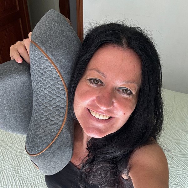 Lillian, a FisioRest customer, smiling and holding the device against her cheek.