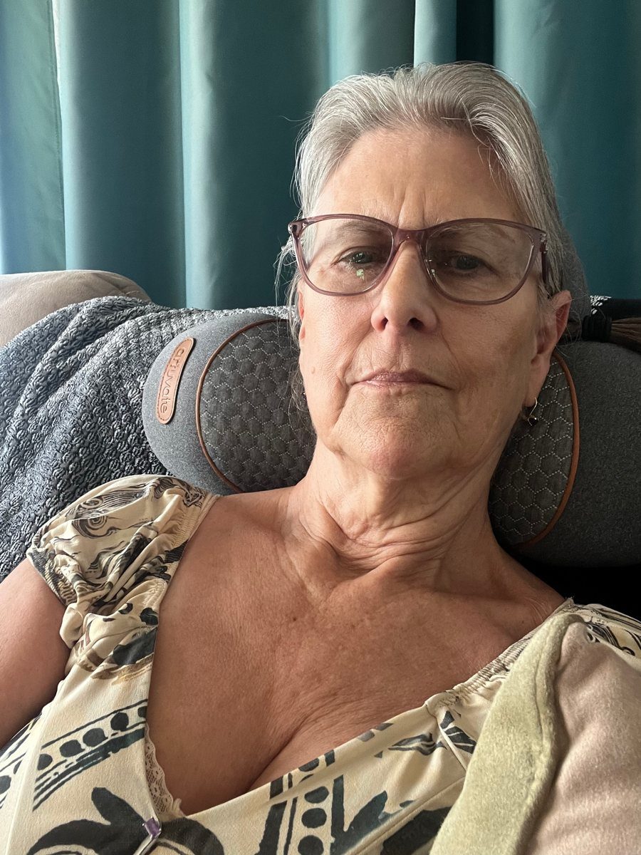 A FisioRest customer resting in an armchair with the device behind the neck.