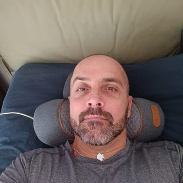 Mark, a FisioRest customer, lying back on the device on his couch.
