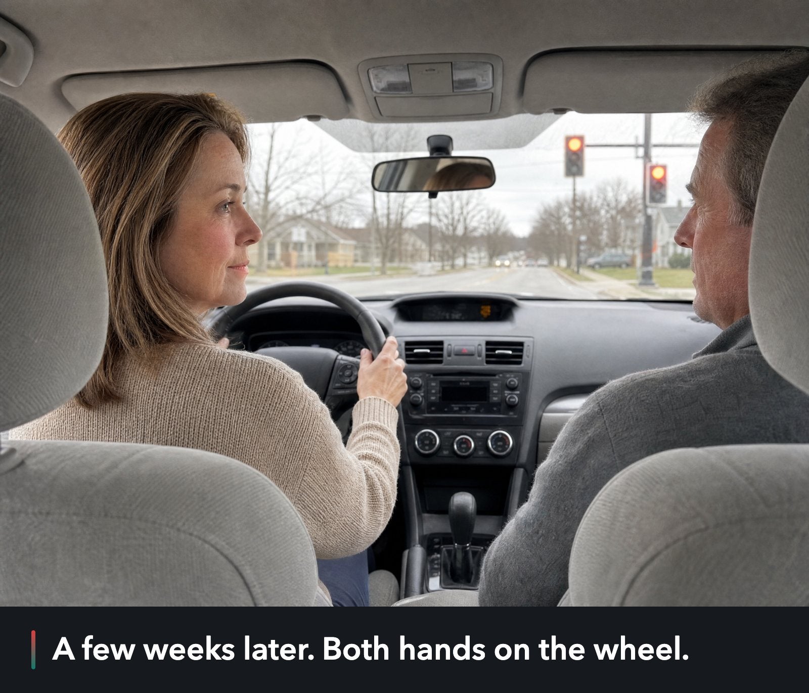The same car at the same red light a few weeks later: she is driving with both hands on the wheel, and her husband looks over at her.